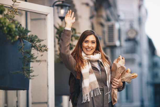 微笑的女士正在向她的朋友打招呼。她手里拿着烘焙产品。图片下载