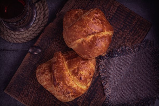 复古的背景与茶，牛角面包在一个由古老的天然木材制成的架子上。布餐巾和旧绳滑。图片下载