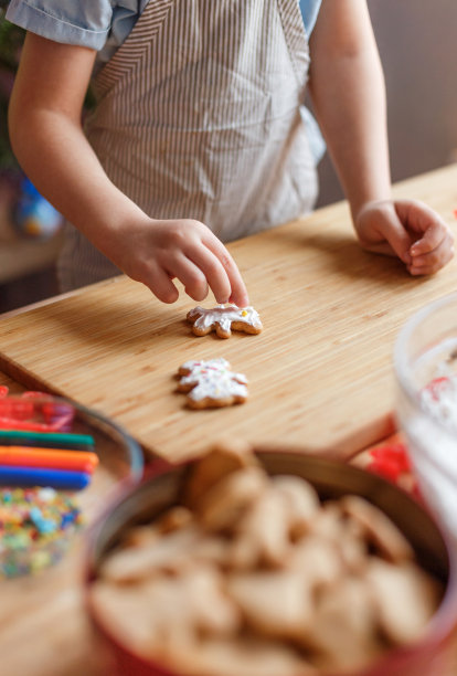 孩子在木桌上装饰新年的姜饼。新年和圣诞节的概念。图片下载