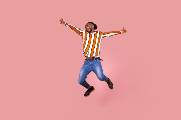 极度高兴兴奋的非裔美国人与脏辫在条纹衬衫高跳广泛张开双手和尖叫感觉自由图片下载
