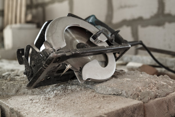 手工圆锯在正在建造泡沫砌块的房屋的木板上图片下载