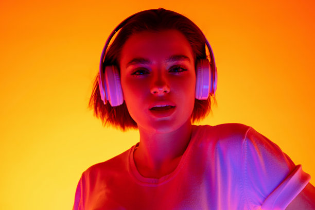 在彩色霓虹灯下，一个白人妇女的肖像孤立在橙色的工作室背景上图片下载