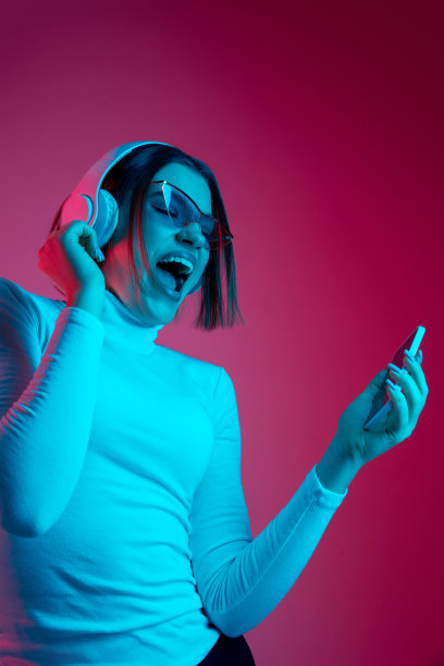 在彩色霓虹灯下，一个白人妇女的肖像被隔离在粉红色的画室背景上图片下载