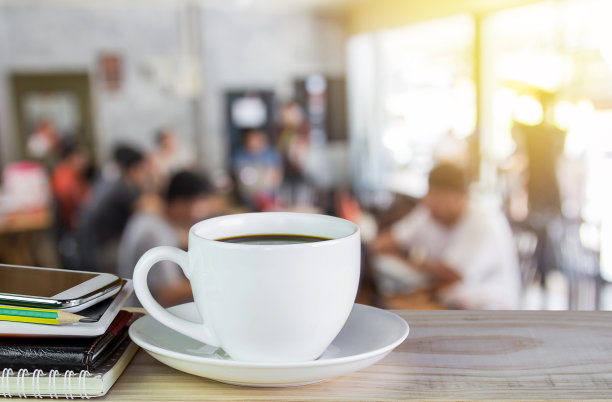 一杯咖啡，笔记本，智能手机放在有早晨阳光的木桌上图片下载