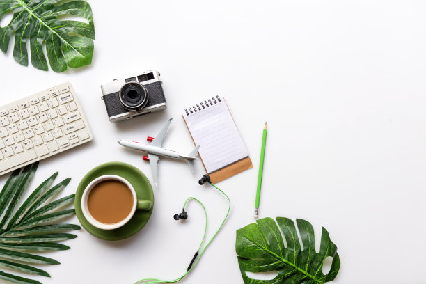 俯视图的旅行者配件和绿色杯咖啡与旅游背包和访问计划旅行目的地和假期，树叶绿色和白色的背景。为文本复制空间。旅游和暑假概念图片下载