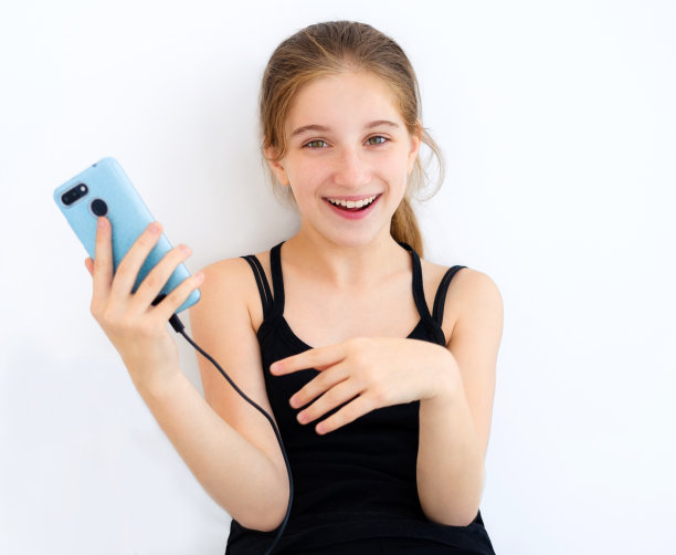 十几岁的女孩拿着蓝色的智能手机图片下载