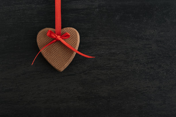 自制的心形饼干，黑色的背景上有红色的丝带。母亲的一天。女人的一天。情人节图片下载