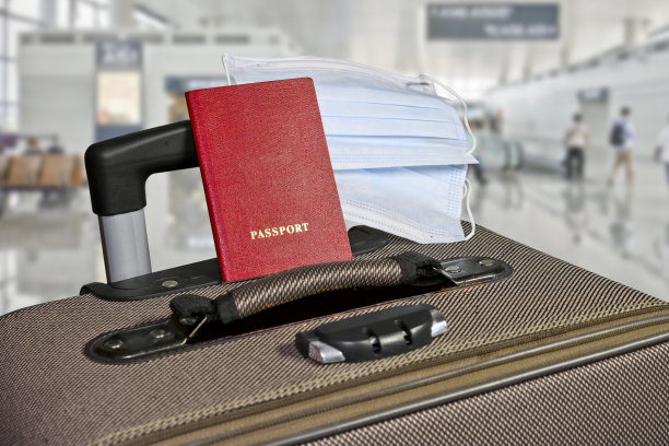 带护照和医用口罩的行李箱在机场候机楼。模糊的背景。新冠肺炎大流行期间的冒险和旅行概念。图片下载