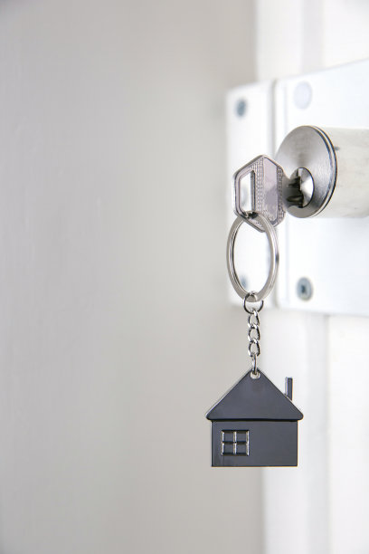 银色的房子钥匙在白色的门上，带小钥匙链的房子，开新房门，家居，投资，房地产概念，空间为文字图片下载