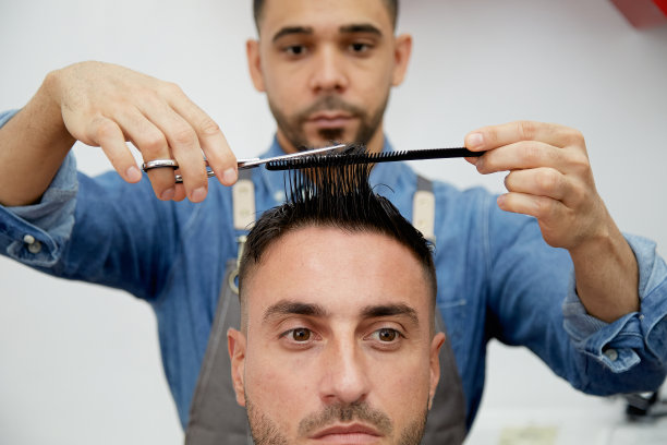 理发师用剪刀剪客户的头发的特写图片下载