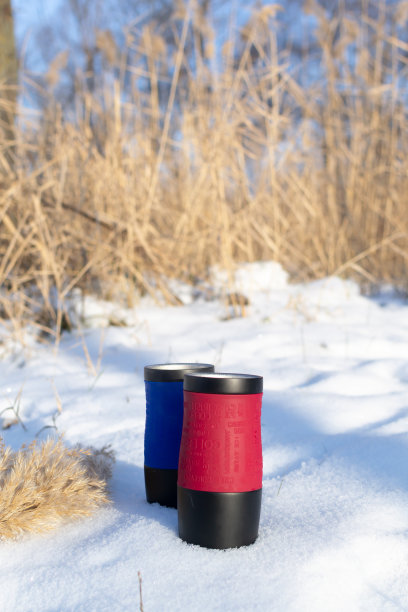芦苇背景上的雪地上，放着两只热饮的热水杯。图片下载