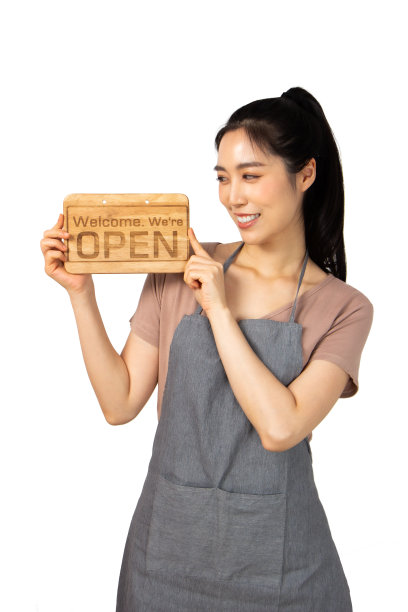 美丽的年轻亚洲女人微笑漂亮的牙齿穿着围裙。一个女人举着木头牌子，大拇指朝上图片下载
