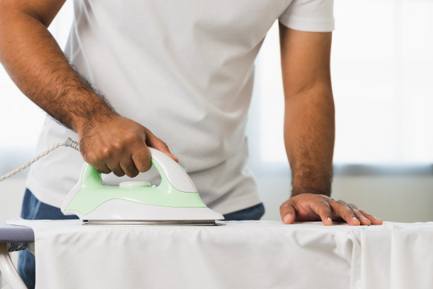 一个用熨斗的男人的手。把衣服熨平。照片关于做家务图片下载
