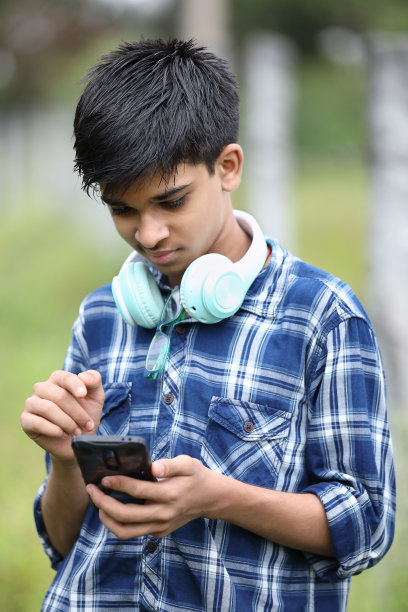 可爱的男孩一边听音乐一边玩手机图片下载