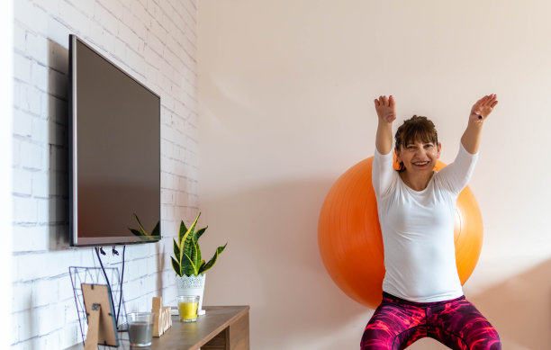 快乐活跃的老年妇女在家里用健身球做运动图片下载