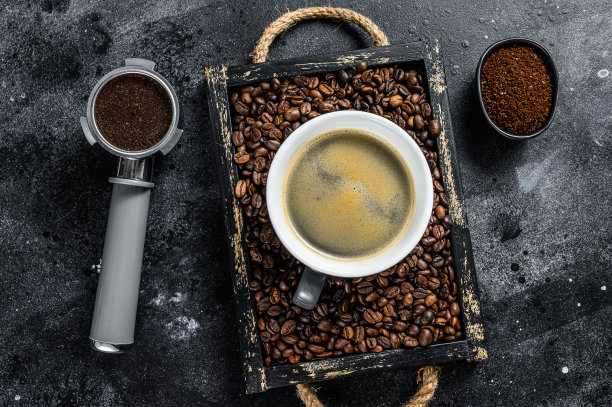 咖啡杯和旧木托盘里的豆子。黑色背景。俯视图图片下载