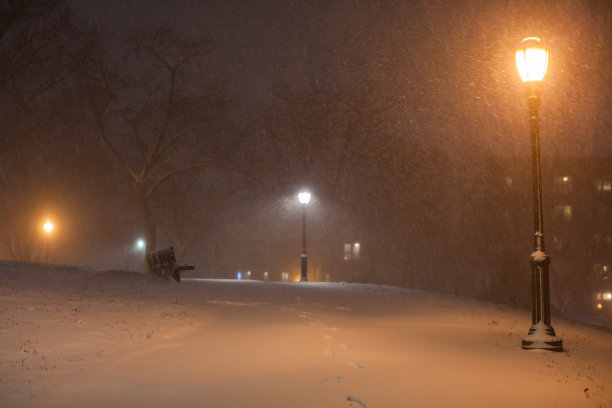 在一场暴风雪中，一条被雪覆盖的小路在黑暗中向远处退去图片下载