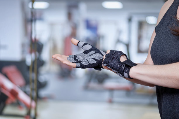 健身运动员戴着手套在体育馆模糊的背景上。图片下载