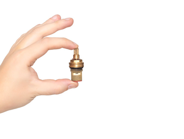 管道工手持一个水龙头轴在一个白色的背景，孤立。概念漏带在搅拌机龙头时更换阀门龙头轴。文本复制空间图片下载