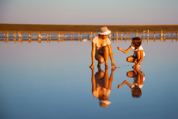两个非常美丽的女孩在一个美丽的透明的湖上寻找东西在一个闪亮的表面图片下载