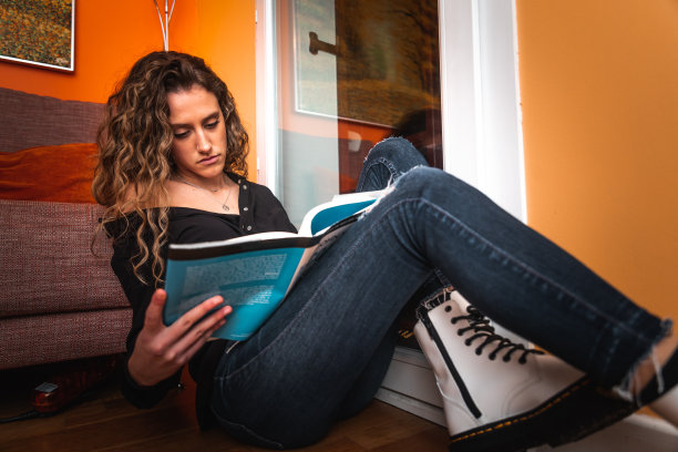 一个年轻女子在窗边看书图片下载