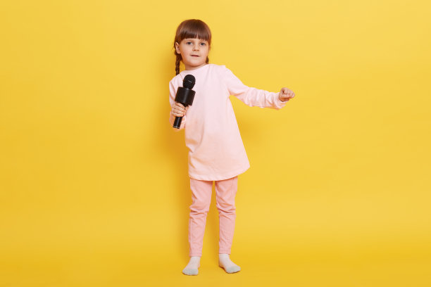 欧洲小女孩拿着麦克风唱歌，看着镜头，在卡拉ok唱歌，表演，制作节目，安排音乐会，小歌手表演。图片下载