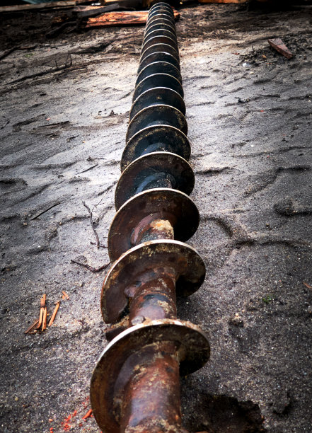 在松软土壤中钻孔的螺旋钻纵向地放在铺路石上图片下载