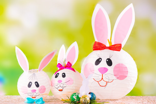 一个家庭的装饰手工复活节兔子在绿色的背景。准备用纸工艺品装饰节日。兔妈妈和她的孩子们图片下载