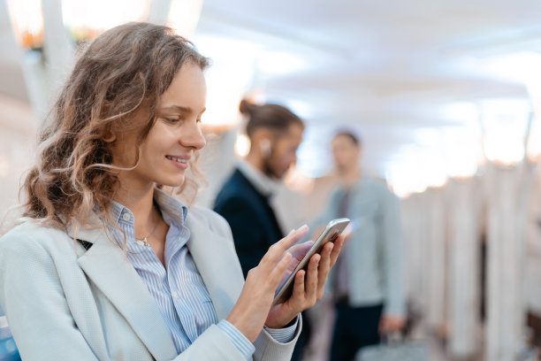 年轻女子在地铁站拿着智能手机图片下载