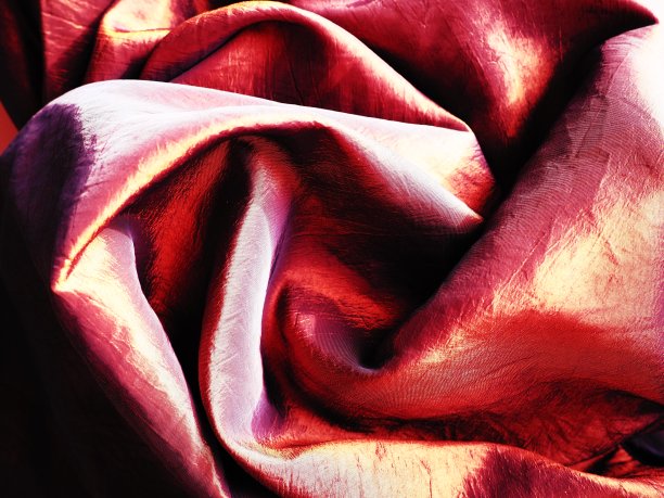 美丽的红色和橙色塔夫绸织物折叠成玫瑰的形状。室内设计选择，布料缝制优雅的衣服和窗帘图片下载