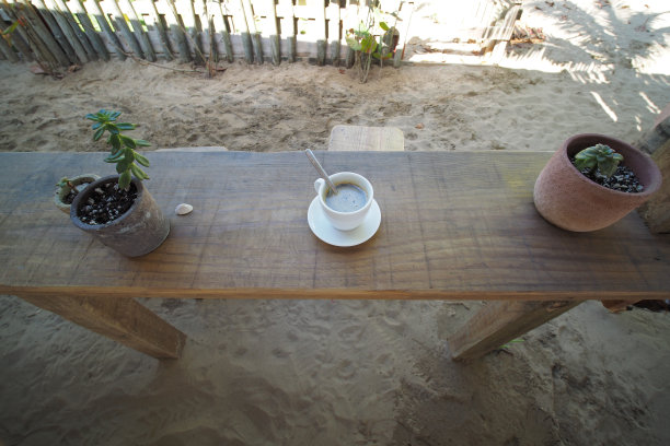 在沙滩上的热带咖啡馆的木桌上喝着咖啡。图片下载