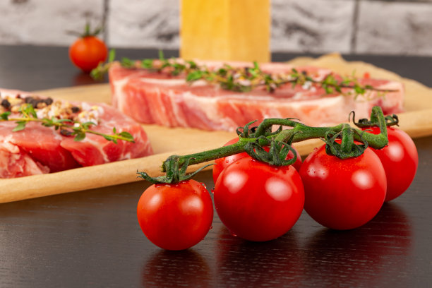 新鲜切好的生猪肉加香料和百里香放在羊皮纸上。旁边是熟西红柿和盐瓶图片下载