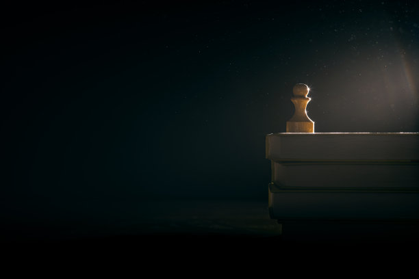 一个白色的木制棋子站在一堆古书上。模拟。文本空白图片下载