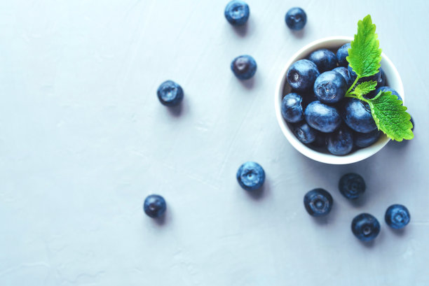 新鲜的蓝莓放在一个白色的碗里。图片下载