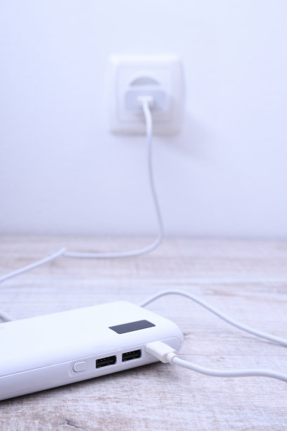 黑色手机电源插在墙上的插座上，以木制为背景进行充电图片下载