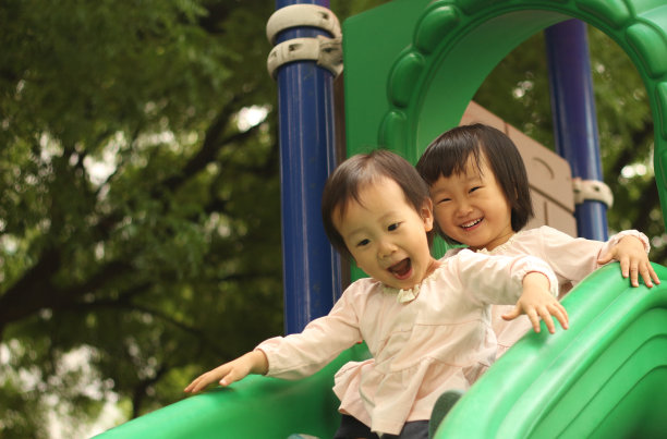微笑的亚洲女孩在春天的公园里玩滑梯。图片下载