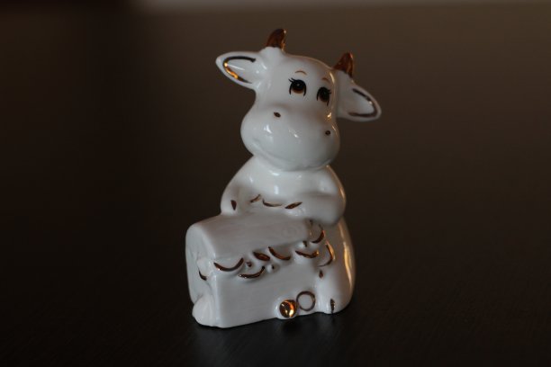 公牛小雕像象征着农历2021年。有角的白奶牛抱着装满财富和健康隔离的盒子图片下载