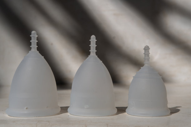 不同大小的硅胶月经杯在极简主义的背景与暗影。可重复使用的环保女性卫生用品。零废物、可持续、无塑料的生活方式图片下载