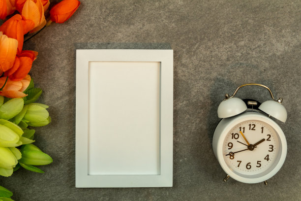 白色框架模型和闹钟在灰色花岗岩与郁金香平lay图片下载