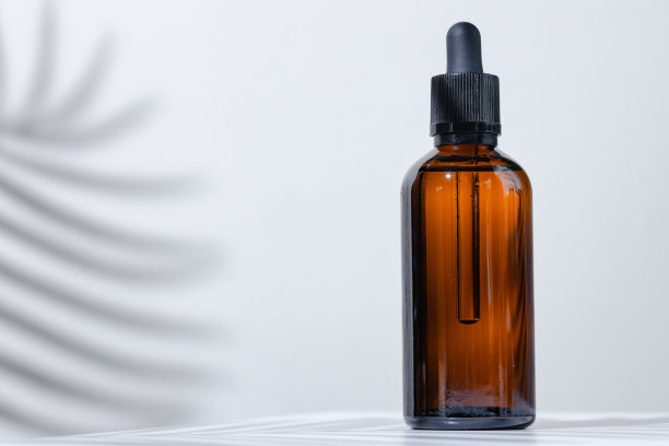 化妆瓶与移液管在白色背景与热带花卉阴影的创意照片图片下载