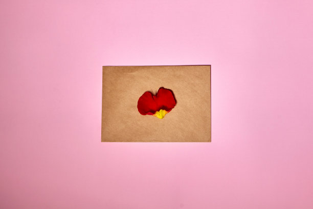 情人节的棕色信封上放着一颗红心。粉色背景，信封和红心。情书或信息的概念。Flat-lay顶视图。为你的文本复制空间。图片下载