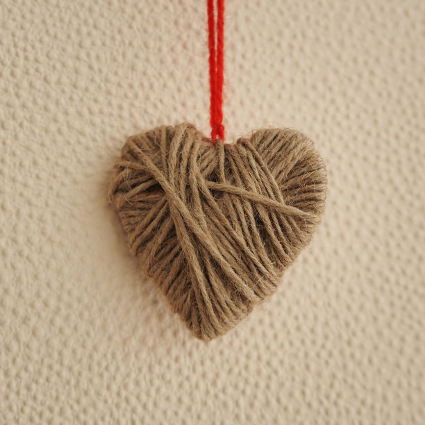 米色的心由羊毛线在米色的背景图片下载