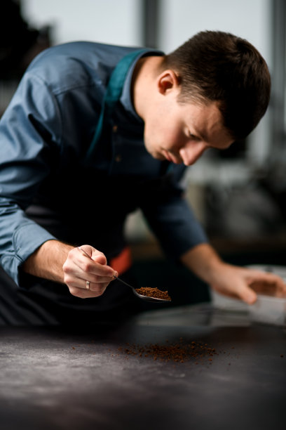 男性拿着盛有颗粒的勺子，把它们洒在桌面上图片下载
