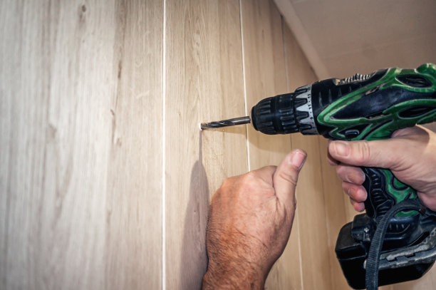 电钻在一块胶合板上钻一个洞。真实的家居装修。空间复制图片下载