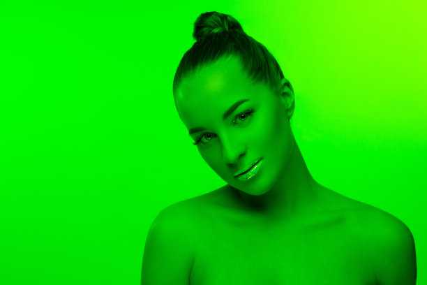 漂亮女人的肖像孤立在绿色的工作室背景霓虹灯，单色图片下载