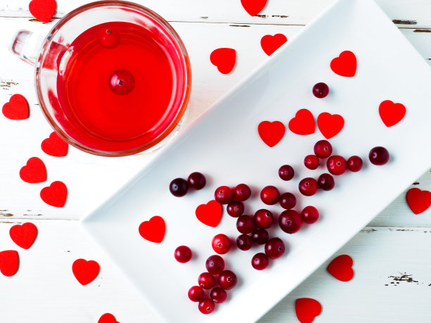 在白色木质背景的长方形盘子上，选择性地选择蔓越莓和红心。图片下载