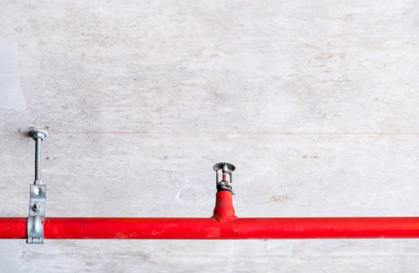 红色金属管上的自动喷水灭火装置。图片下载