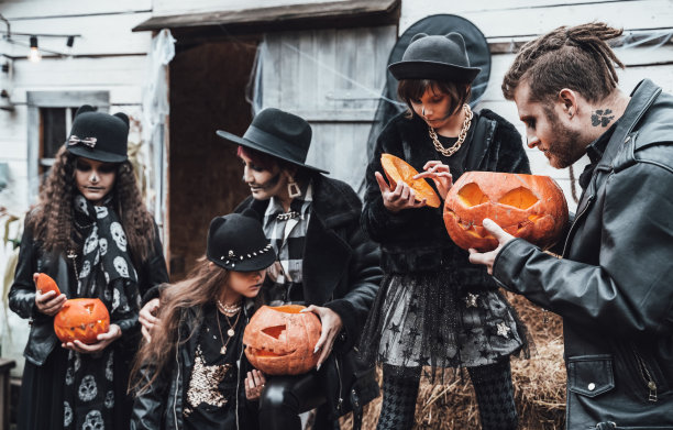 可怕的家庭，母亲，父亲，女儿们都在庆祝万圣节。南瓜南瓜灯。恐怖的黑色骷髅脸妆，时尚的女巫服装。恐怖，有趣的儿童派对。干草在大街上。帽子,夹克图片下载