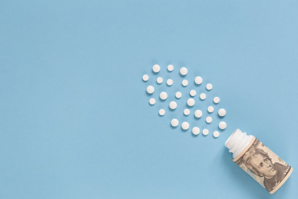 装有美元和许多白色药片的药瓶。医保的概念，药费高。孤立在蓝色背景上。图片下载