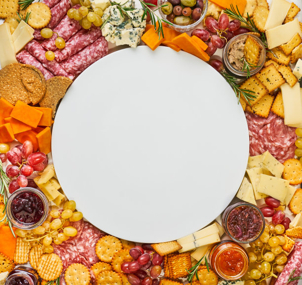 空盘子周围有各种奶酪，意大利腊肠，饼干，俯视图图片下载